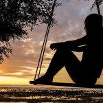 silhouette of woman on swing during golden hour